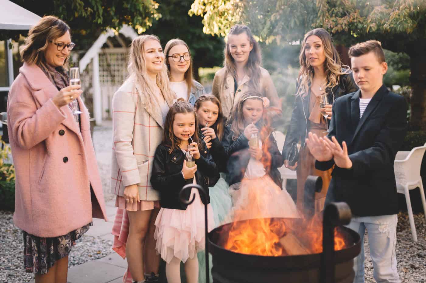 blog post featured image Sam and Kirk and family warm their hands over a fire at Akarua Wines and Kitchen by Artisan during their wedding reception