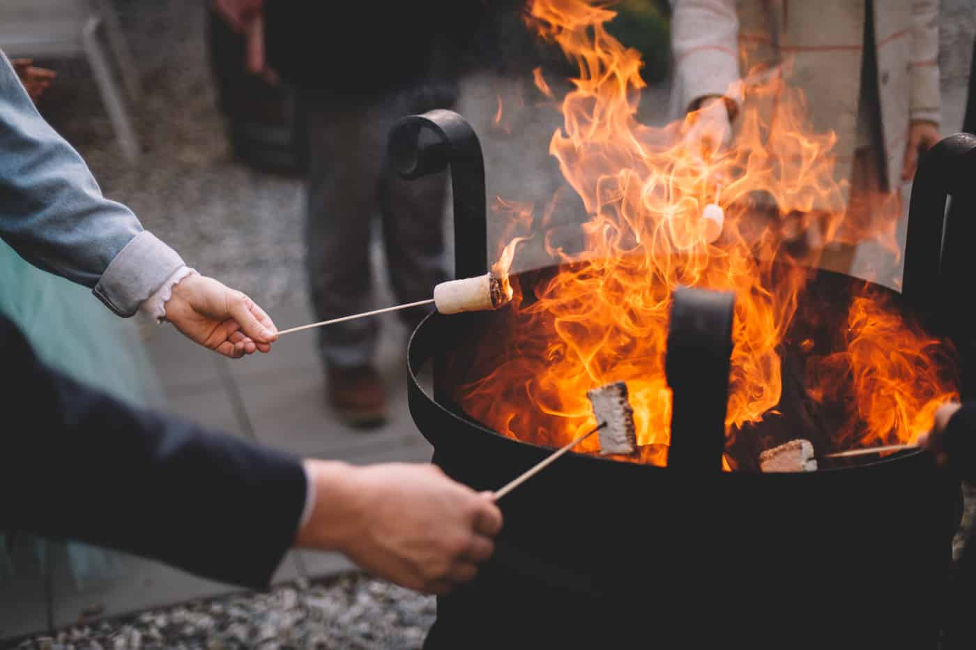 Sam and Kirk and family toast marshmallows over a fire at Akarua Wines and Kitchen by Artisan during their wedding reception